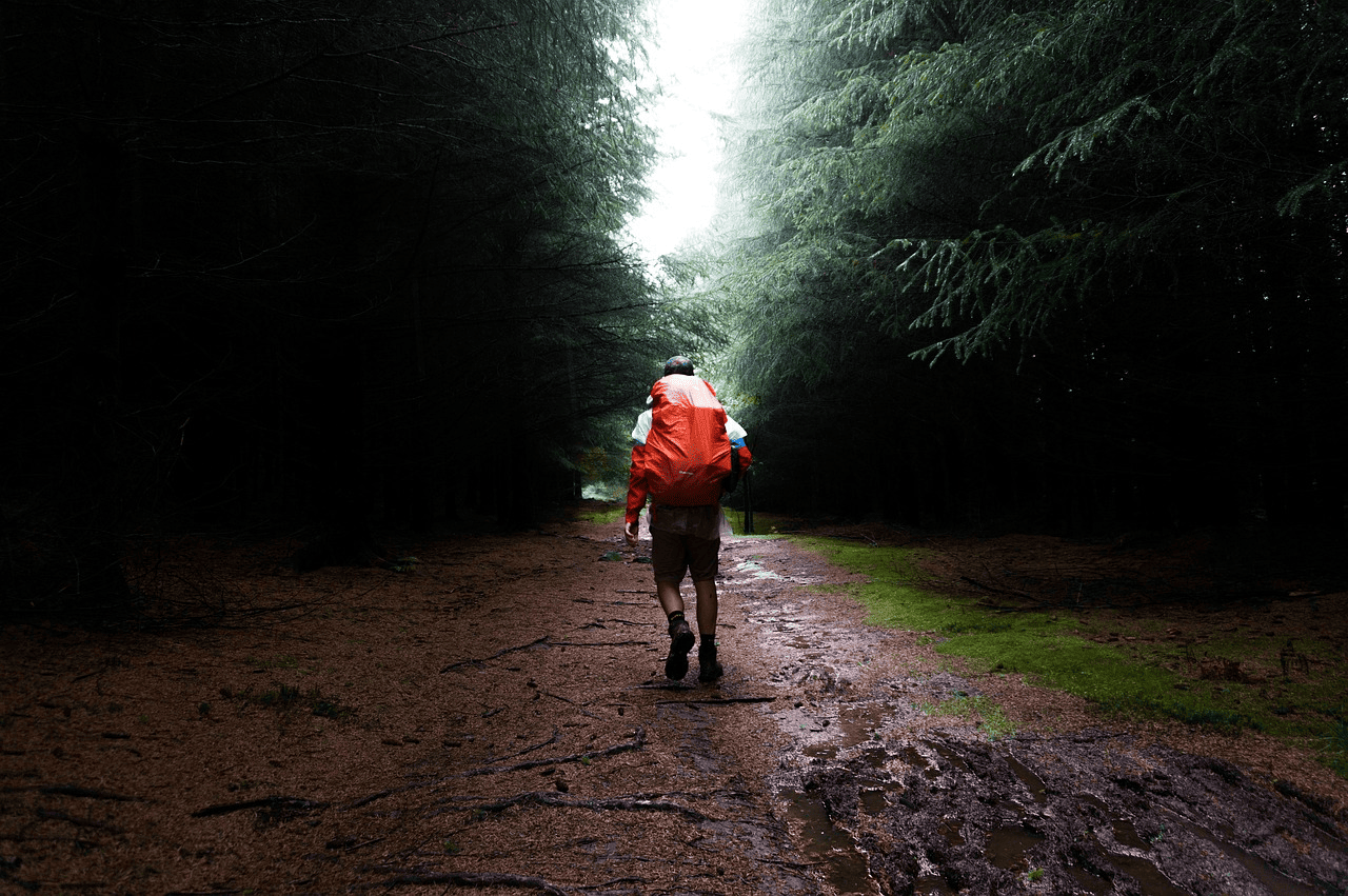 person walking in a muddy road with backpack
