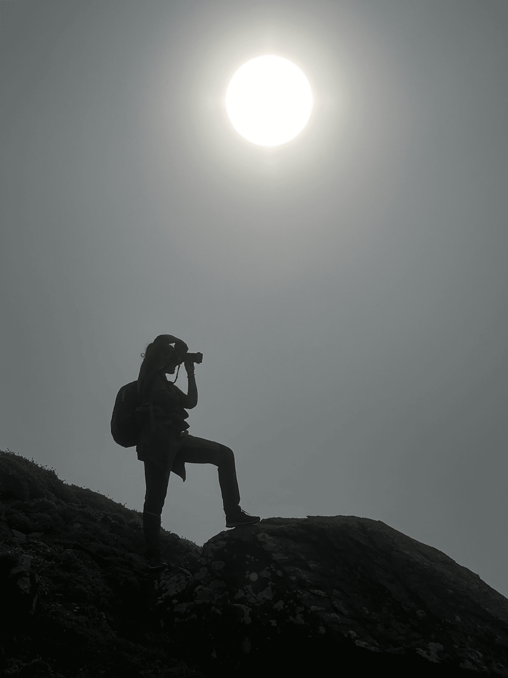 grey image of women clicking a picture under the sun