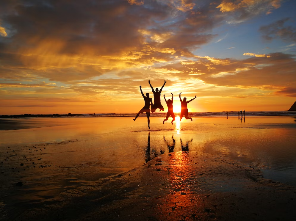 people jumping on beach during sunset time
